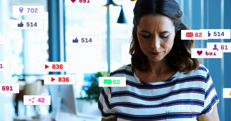Checking mid adult woman in navy-white T-shirt reading alerts in office, with social media overlays....