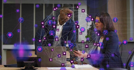 Leaning man in suit and woman in blazer discussing in office holding laptop smartphone AR overlay....