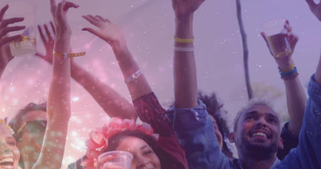 Raising friends' arms while holding clear cups under canopy, wearing floral headband and wristbands....