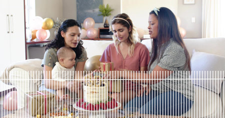 Celebrating three women and baby on light sofa in living room, cake, gifts, striped overlay. Dessert, balloons, present, decor, warmth, cozy, intimateの写真素材