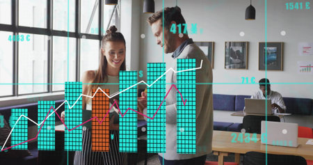 Reviewing overlaid charts, man in blazer and teen in striped pants using tablet at office table....