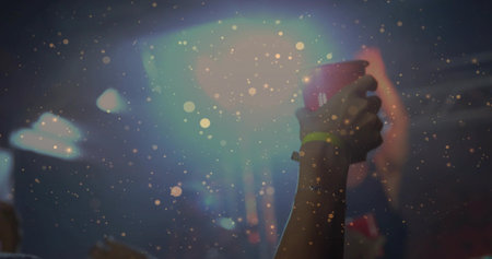 Raising female arm holding red cup with neon wristband and bracelet at concert, copy space. Forearm,...