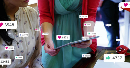 Holding tablet woman mint-dress red-cardigan at wood table with white paper stapler and like counts....