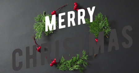 Displaying wreath centered on dark tabletop, with green sprigs, red berries and white MERRY letters....