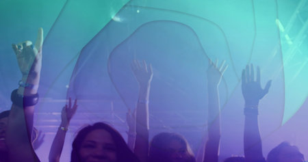Cheering crowd of concertgoers raising hands at front of club, with wristbands and projection....