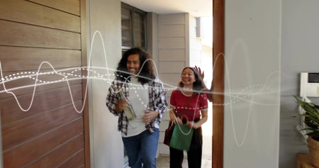 Walking couple smiling, carrying green tote in foyer, wearing plaid shirt red top, dotted waveform....