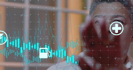 Studying mature man in light shirt viewing screen in office, with teal charts, icons, copy space....