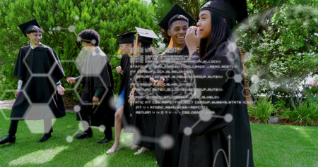 Walking grads wearing black gowns and caps across campus lawn, dress showing, with hexagon graphics....