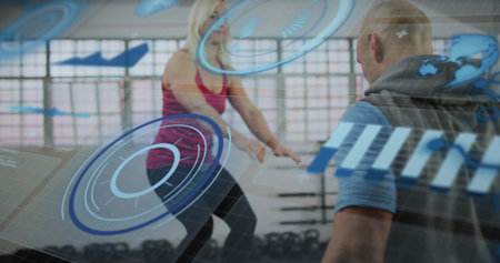 Squatting woman in pink tank, leggings at gym with trainer in blue shirt, kettlebells and HUD....