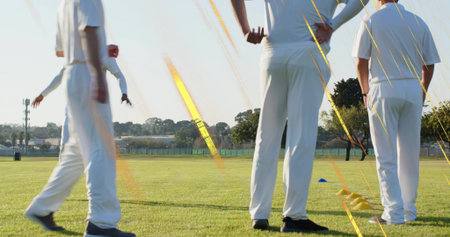 Walking four athletes in white sportswear training on field, with yellow hurdles and blue cones....
