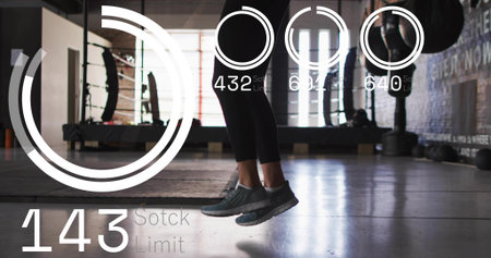 Jumping woman's lower legs in dark leggings and shoes hovering above concrete gym floor, with HUD....