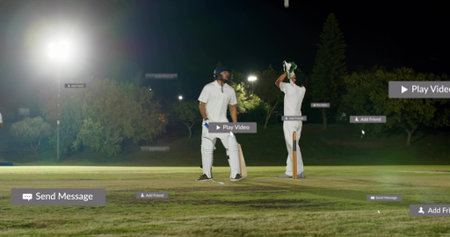 Standing players wearing white pads holding bat lifting helmet by stumps under lights, UI overlays....