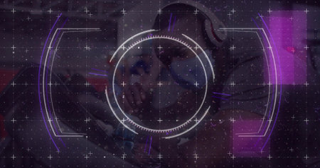 Displaying central HUD reticle over purple lounge, showing seated man wearing hoodie and headphones....