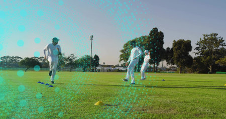 Practicing group of four cricketers in white uniforms running on local cricket ground, with cones....