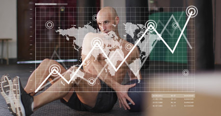 Twisting shirtless man in black shorts holding medicine ball on gym floor, showing data overlay....
