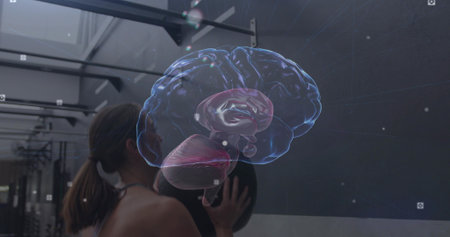 Holding medicine ball, woman in sports bra performing wall-ball at gym, showing 3D brain hologram....