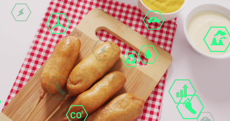 Displaying four corn-dogs on board over gingham cloth at table, with sauces and green overlays....