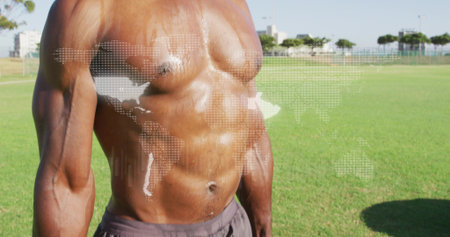 Standing shirtless man showing torso and dark shorts on sports field, with dotted world map overlay....