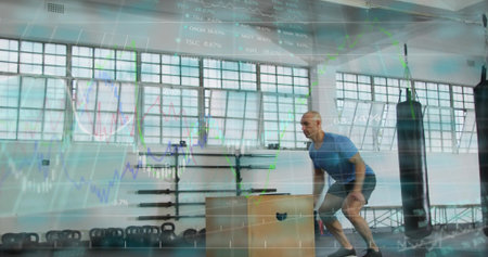 Crouching man wearing blue tee, shorts preparing jump at gym, plyo box, data overlay, copy space....