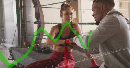 Wrapping trainer applying red wraps to athlete on ring ropes, sports bra, leggings, green overlay....