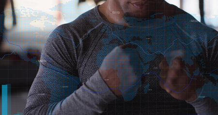 Raising fists, boxer wearing long-sleeve shirt with hand wraps at gym, showing world map overlay....