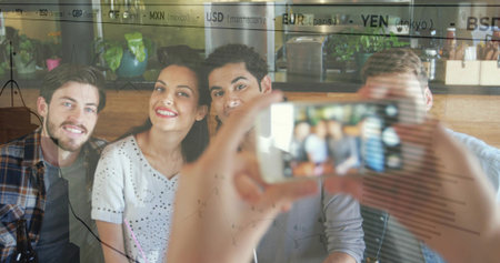 Smiling friends posing for selfie at cafe bench, holding smartphone with financial overlay. Group,...