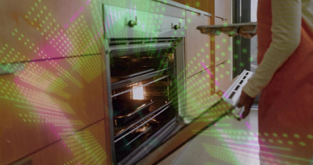 Holding oven door, woman in pink apron guiding child placing metal tray into oven in kitchen....