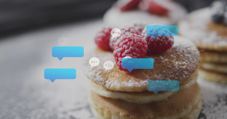 Showing three pancakes dusted with powdered sugar topped with raspberries on tabletop, chat bubbles....