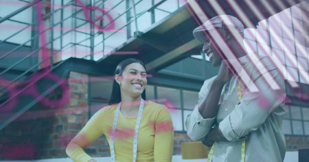 Talking tailors in loft wearing yellow top and cap measuring tapes pink sketches on glass partition....