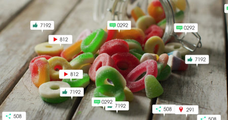Spilling sugar-coated gummy rings across rustic wooden tabletop, with glass jar and social overlays....