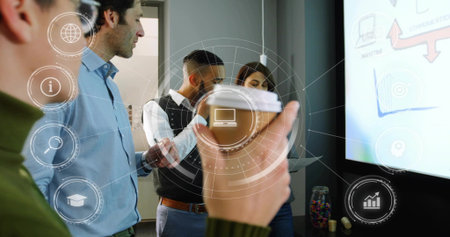 Standing team in business casual discussing slide on wall display, holding coffee cup with UI....