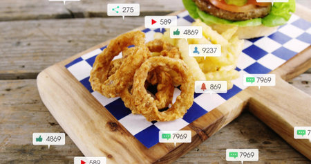 Showing stack of crispy onion rings resting on blue-white paper on wooden board, with social badges....