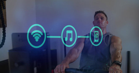 Cycling man on exercise bike at gym, wearing sleeveless hoodie, tracker, hologram icons, copy space....