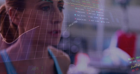 Analyzing adult woman in light-blue thin-strap athletic top viewing translucent data overlay in gym....