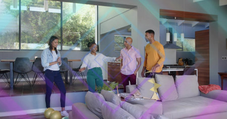 Chatting group of four adults standing in modern open-plan living area with sofa and gold balloons....