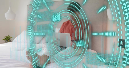 Sitting man wearing coral top and light shorts holding laptop in bedroom, with cyan AR HUD. Person,...