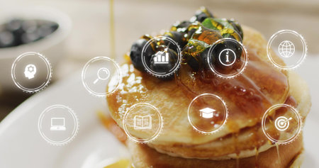 Pouring syrup over stack of pancakes on counter, with blueberries, pistachios and UI icons....