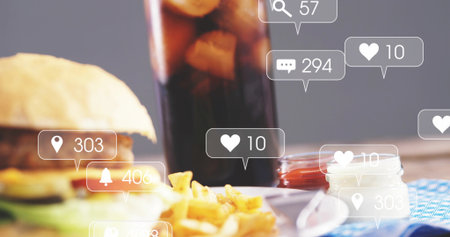 Showing close-up burger and fries on wooden table with soda, condiment jars, social icons. Food,...