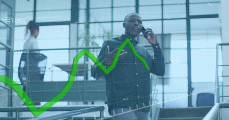 Speaking into phone, man in dark shirt gesturing by office glass and stairs, with green overlay....