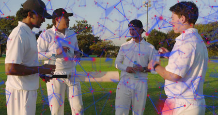 Standing four cricketers in white planning tactics on grassy field, with bat, ball, water bottles....