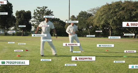 Running two cricketers wearing white kit practicing on grass field, showing AR labels and cones....