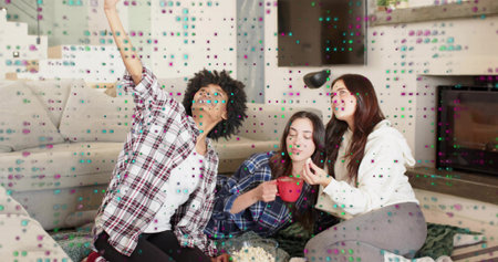 Taking selfie with phone, women in plaid, white-hoodie holding red mug sharing popcorn on home rug....
