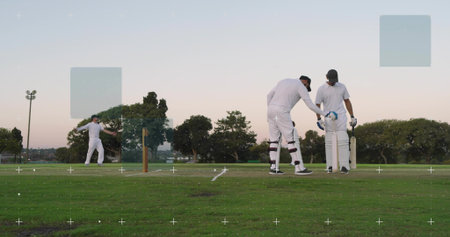 Running bowler delivering ball from left pitch at dusk, batsmen in white cricket pads, copy space....