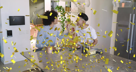 Offering toast, men in blue top and white tee sitting at kitchen island, gold confetti falling....