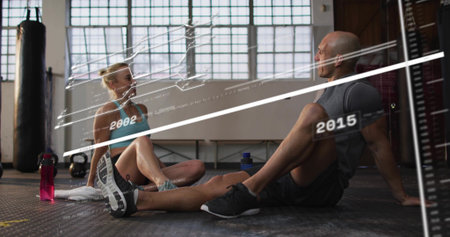 Resting workout partners sitting on gym floor, wearing sports bra, showing pink bottle, overlay....