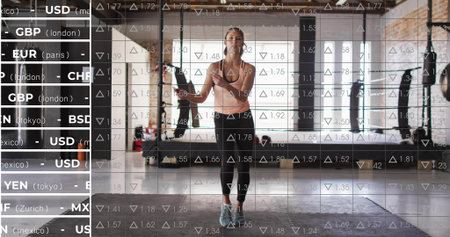 Jumping woman in pink top and black leggings skipping rope at center brick gym, showing ticker....