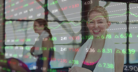 Smiling woman wearing dark sports top holding white towel at gym, market data overlay, copy space....