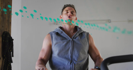 Exhaling man in sleeveless gray hoodie walking on treadmill at gym, teal droplet graphic showing....