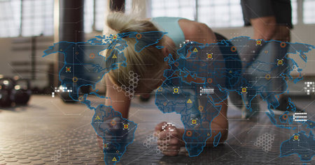 Holding forearm plank mid-adult woman wearing light-blue sports-bra dark shorts in gym, kettlebells....