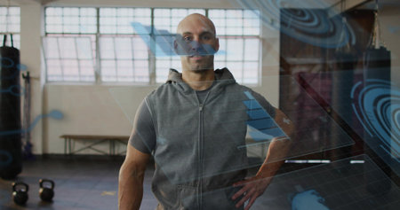 Standing man in gray sleeveless zip hoodie over shirt, posing in gym with kettlebells, AR-overlays....